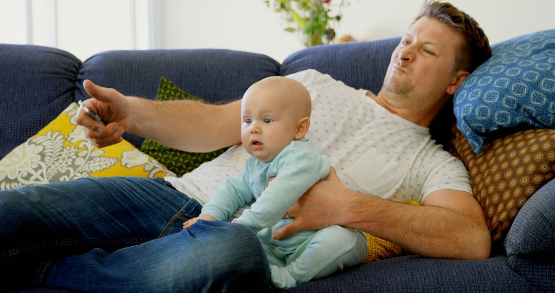 Young Father Holding Baby on Couch Watching TV - Free Images, Stock Photos and Pictures on Pikwizard.com