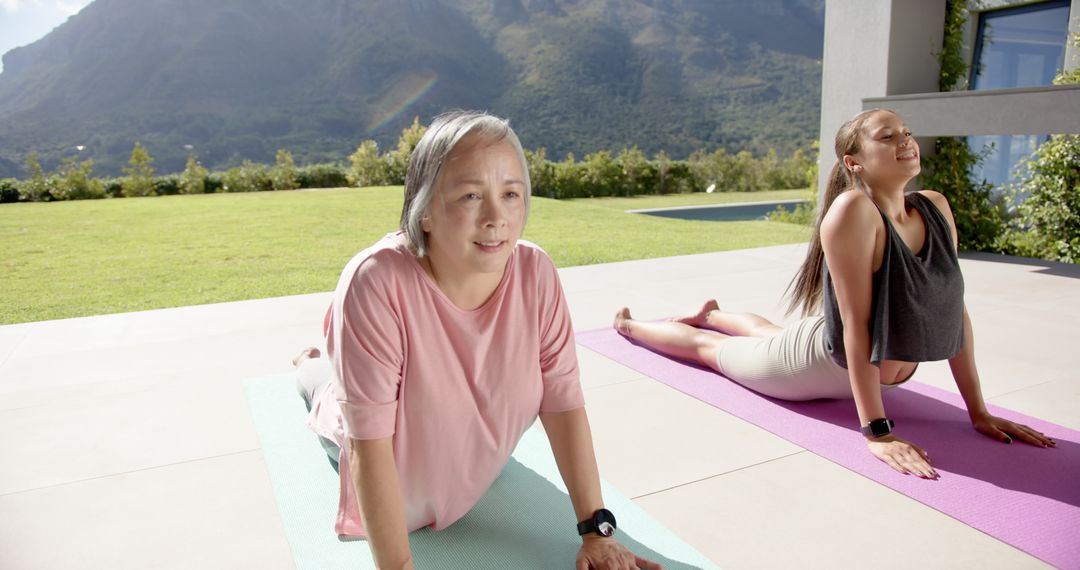 Elderly and Young Woman Practicing Yoga Outdoors