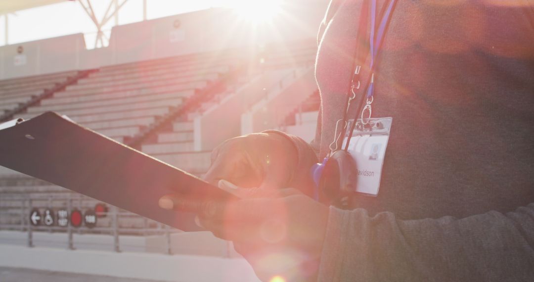 Person Checking Clipboard at Empty Stadium During Sunrise - Free Images, Stock Photos and Pictures on Pikwizard.com