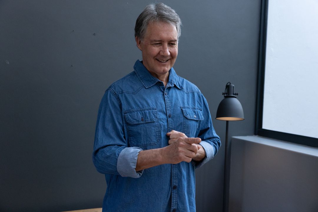 Senior Man Standing in Minimalist Room With Denim Shirt