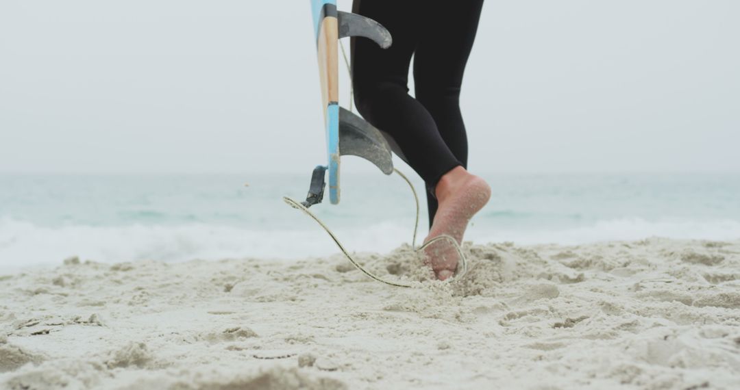 Surfer Strolling on Sandy Beach with Surfboard in Hand