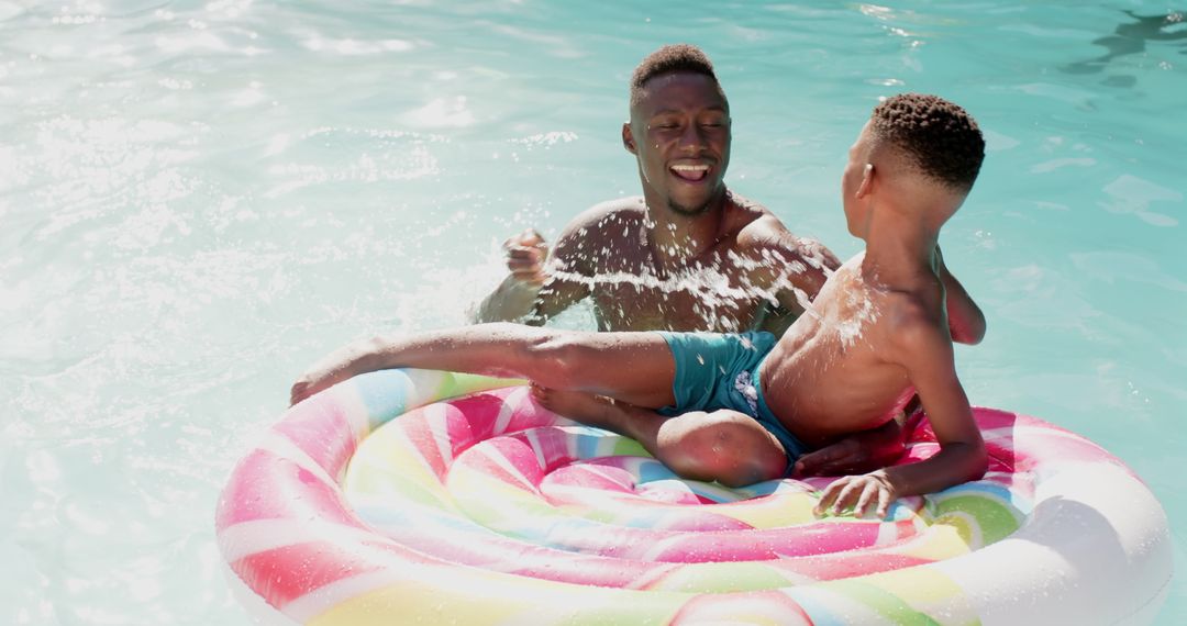 Father and Son Having Fun in Pool with Colorful Inflatable Float