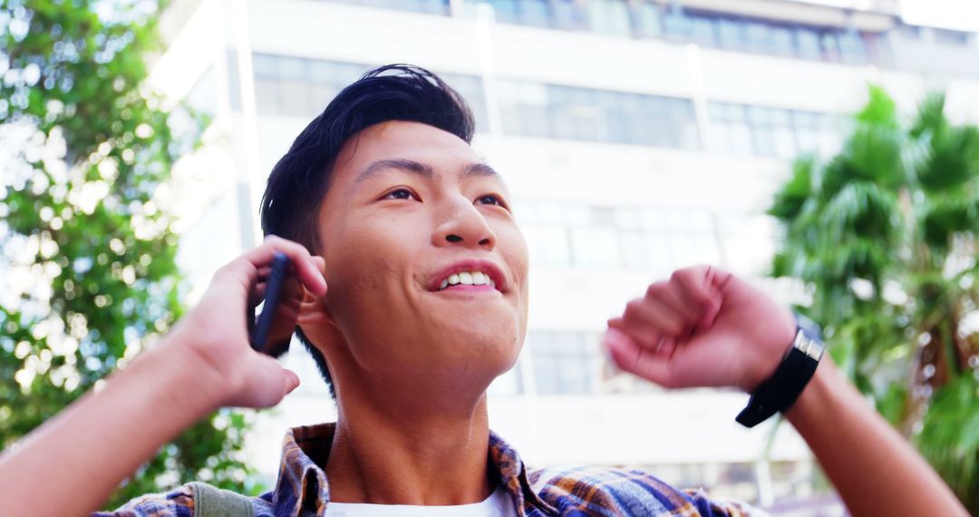 Excited Young Asian Man Celebrating Success Over Phone Outdoors - Free Images, Stock Photos and Pictures on Pikwizard.com