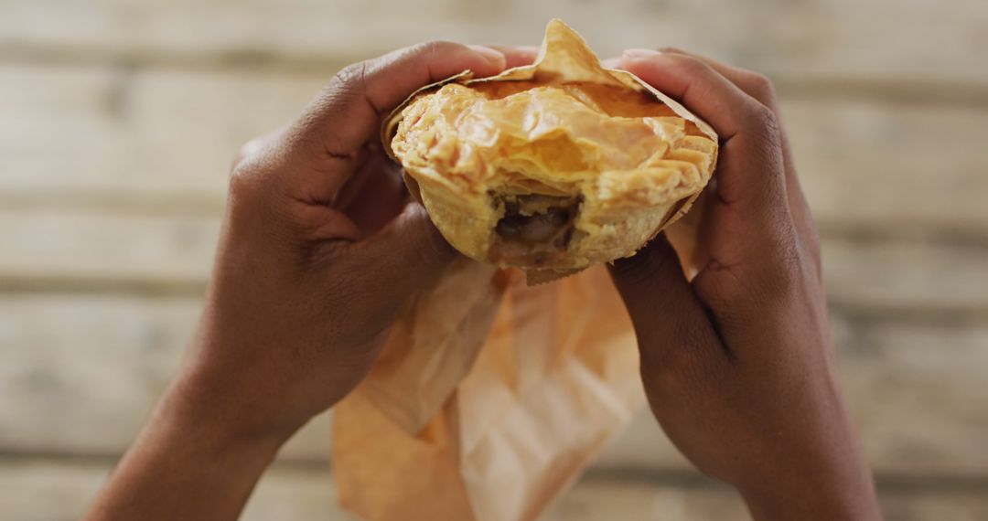 Hands Holding Warm Savory Pie on Rustic Table