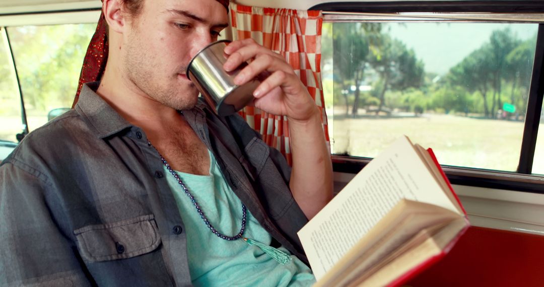 Young Man Drinking Coffee and Reading Book in Camper Van - Free Images, Stock Photos and Pictures on Pikwizard.com