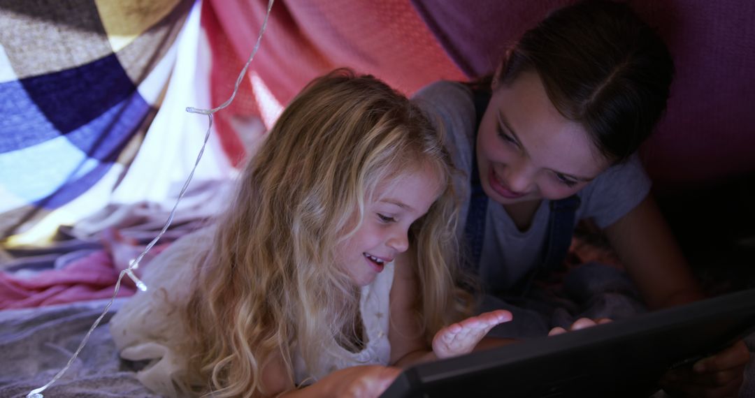 Sisters Enjoying Playtime with Digital Tablet in Homemade Fort - Free Images, Stock Photos and Pictures on Pikwizard.com