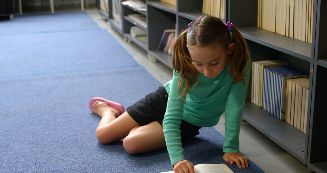 Young Girl Reading Book on Floor in School Library