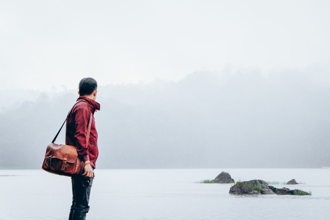 Man in Red Jacket Gazing at Misty River