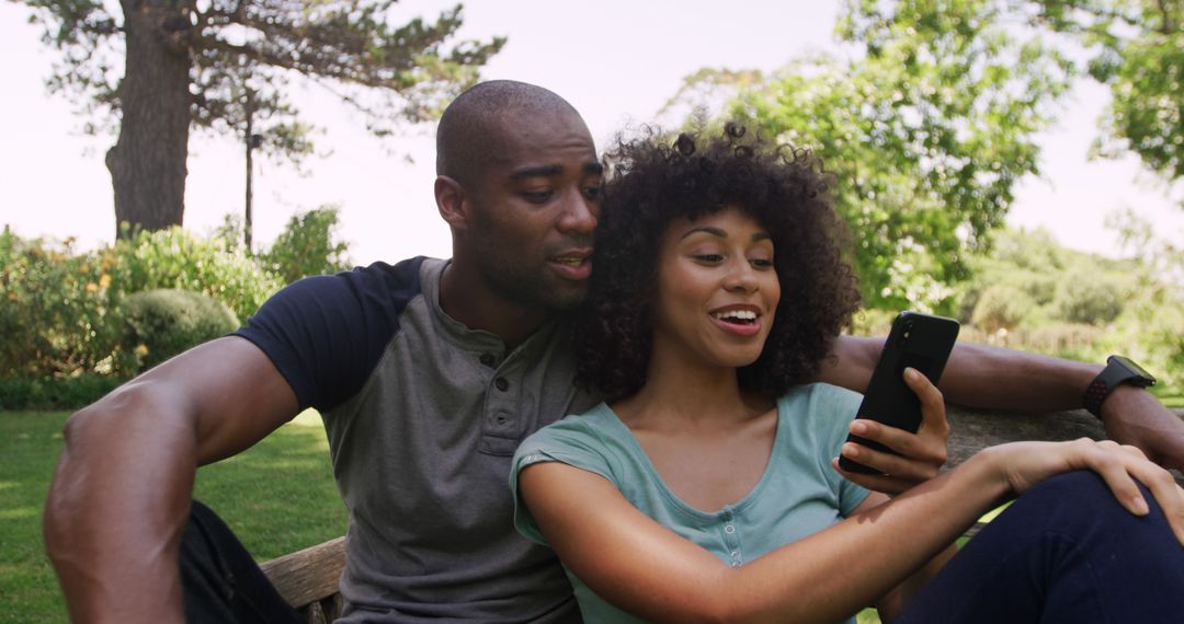 Smiling Couple Using Smartphone in Garden