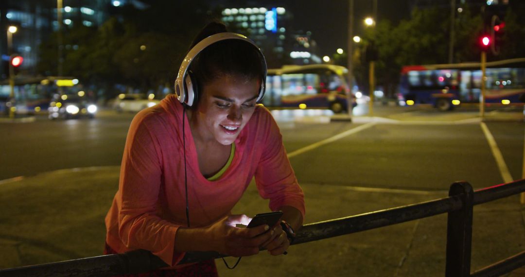 Woman Running at Night Wearing Headphones and Using Smartphone - Free Images, Stock Photos and Pictures on Pikwizard.com