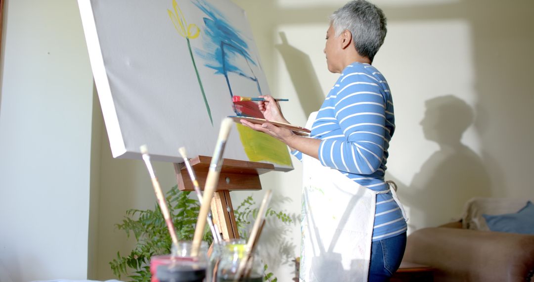 Senior Woman Engaged in Painting on Large Canvas at Home