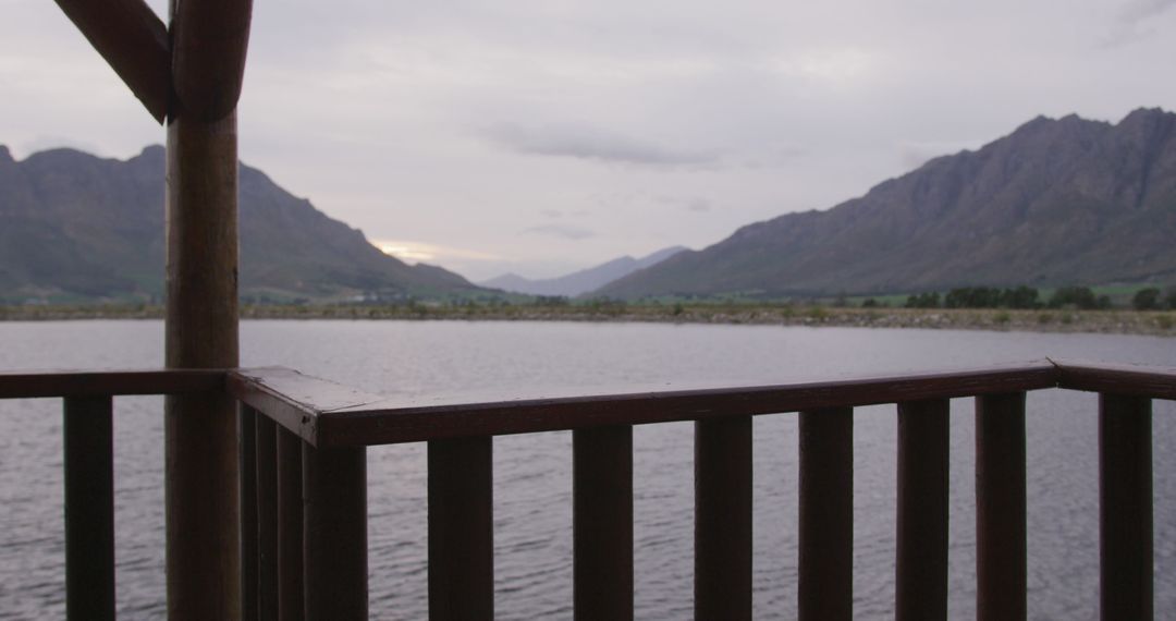 Serene Lakeside View from Wooden Balcony House, Mountains in Background - Free Images, Stock Photos and Pictures on Pikwizard.com