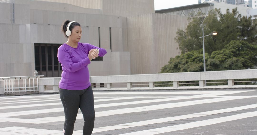 Woman Checking Smartwatch While Walking on Urban Plaza in Purple Top
