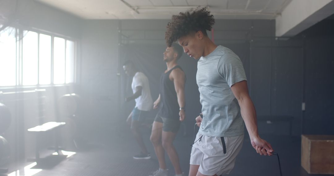 Diverse Group of Men Focused on Jump Rope Workout in Gym