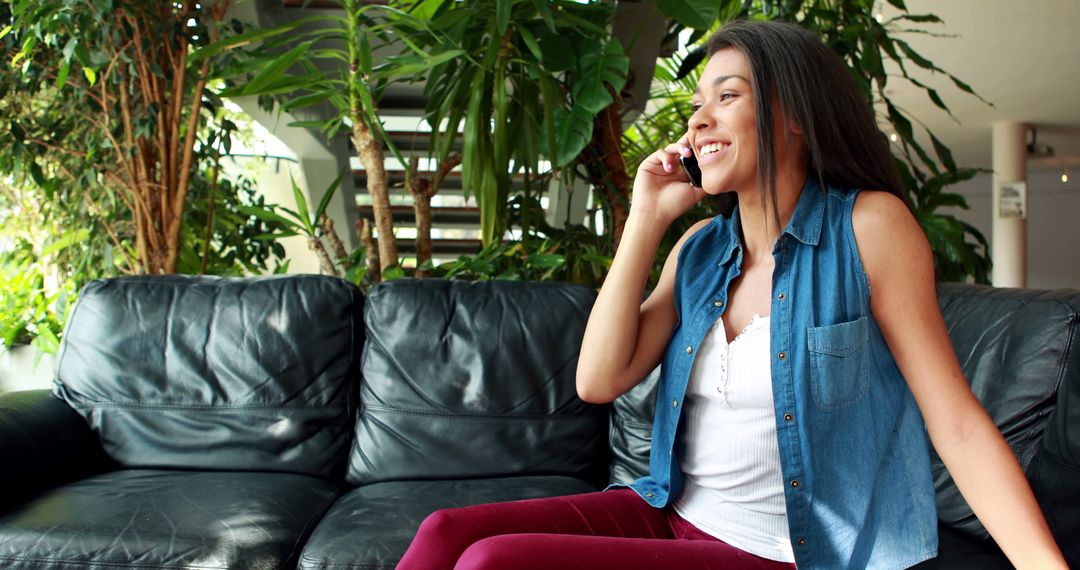 Smiling woman talking on phone while sitting on sofa in bright living room - Free Images, Stock Photos and Pictures on Pikwizard.com