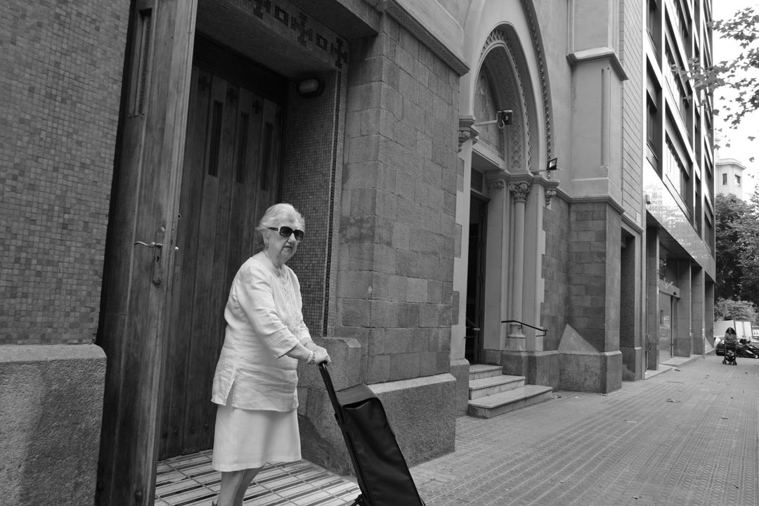 Elderly Woman Walking Along Urban Street with Trolley Bag - Free Images, Stock Photos and Pictures on Pikwizard.com