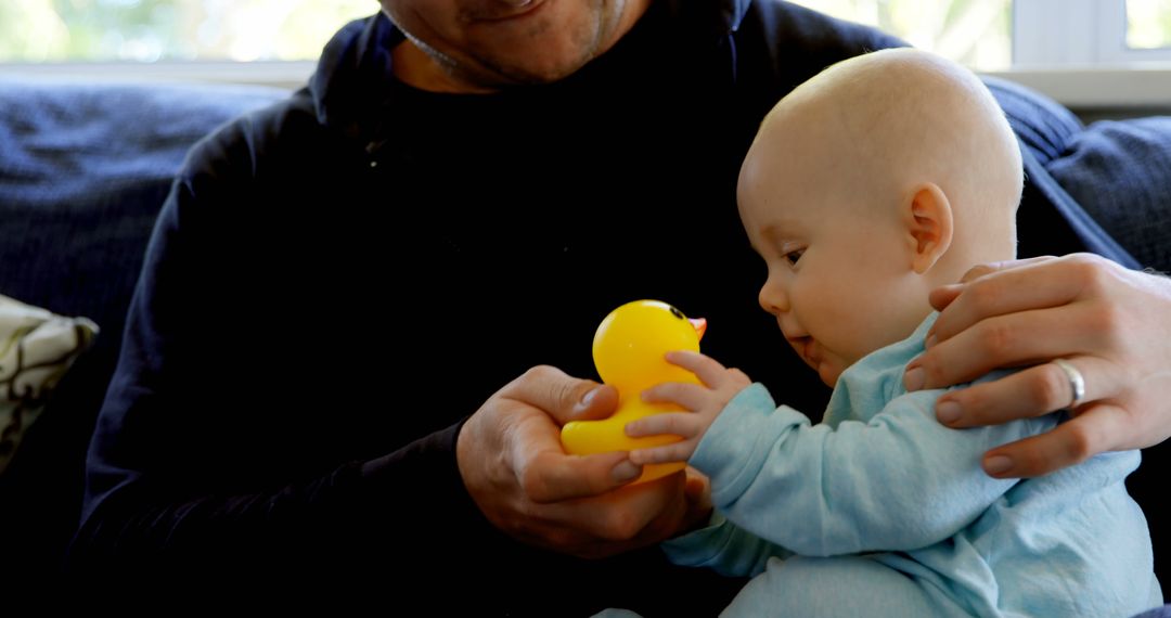 Father bonding with baby holding yellow rubber duck - Free Images, Stock Photos and Pictures on Pikwizard.com