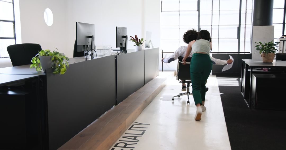 Co-workers Enjoying Office Fun with Chair Ride Adventure