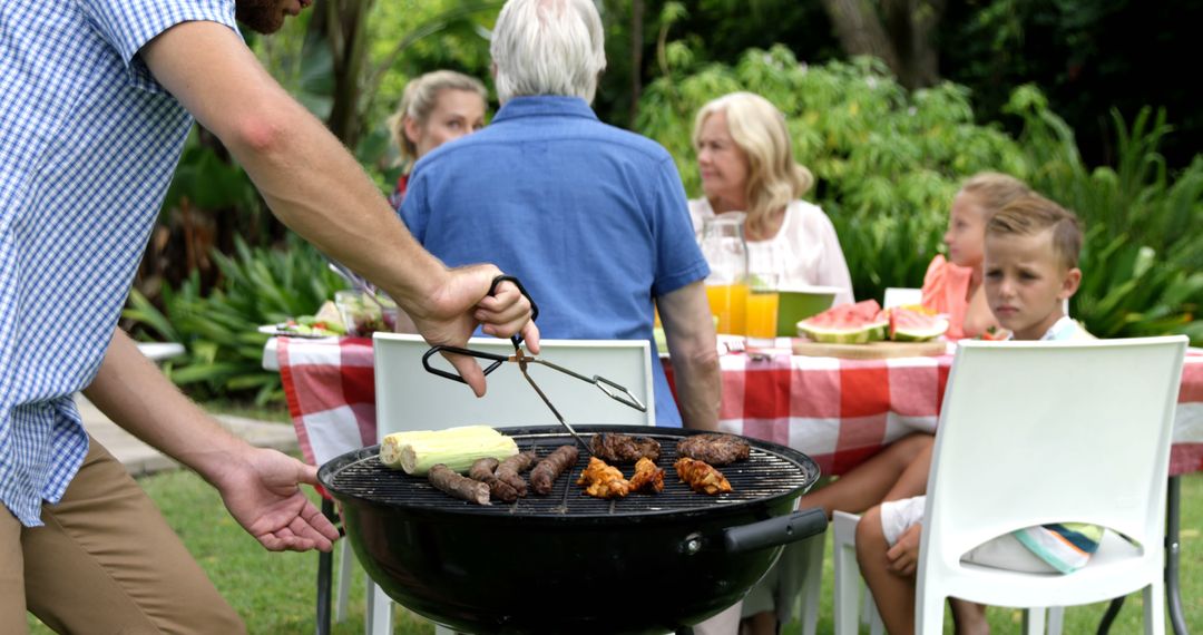 Family Enjoying Outdoor Barbecue with Grilling Meat - Free Images, Stock Photos and Pictures on Pikwizard.com