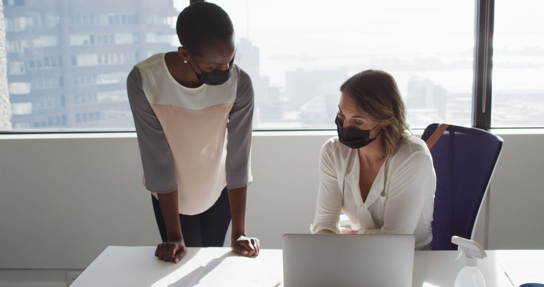 Businesswomen in Protective Masks Collaborating in Modern Office - Free Images, Stock Photos and Pictures on Pikwizard.com