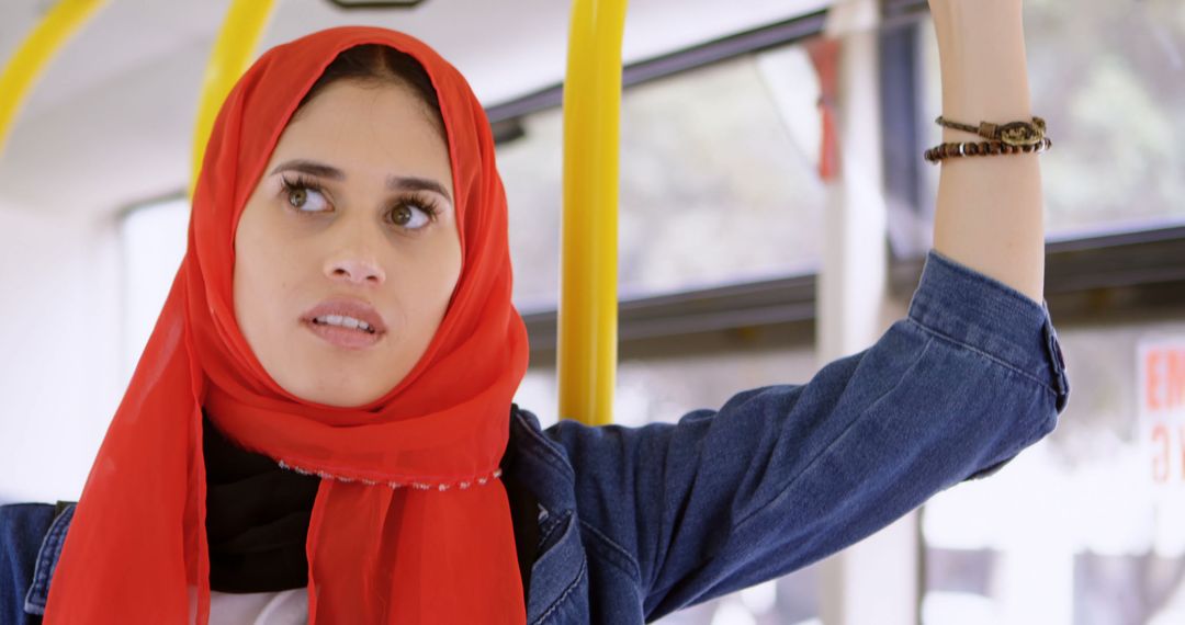 Young Woman in Red Hijab Holding Rail on Public Bus - Free Images, Stock Photos and Pictures on Pikwizard.com