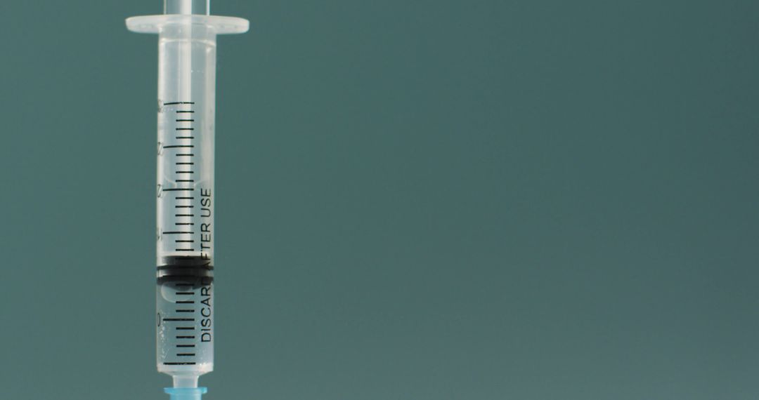 Close-Up of Medical Syringe with Clear Liquid on Turquoise Background - Free Images, Stock Photos and Pictures on Pikwizard.com