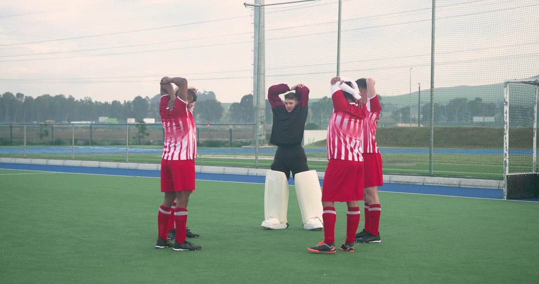 Field Hockey Teammates Stretching with Goalkeeper on Turf