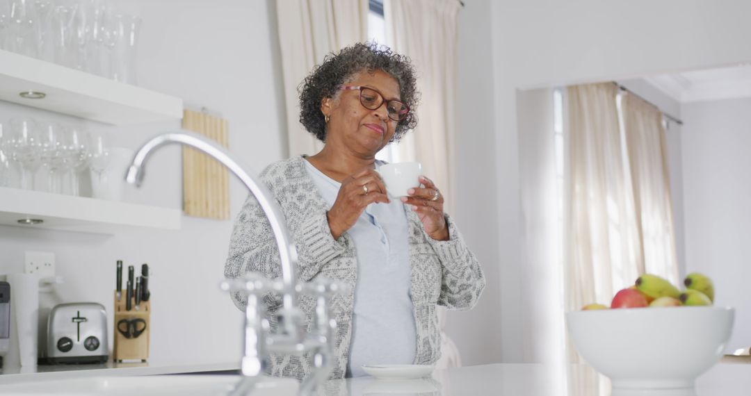 Content Senior Woman Enjoying Morning Coffee in Bright Kitchen - Free Images, Stock Photos and Pictures on Pikwizard.com