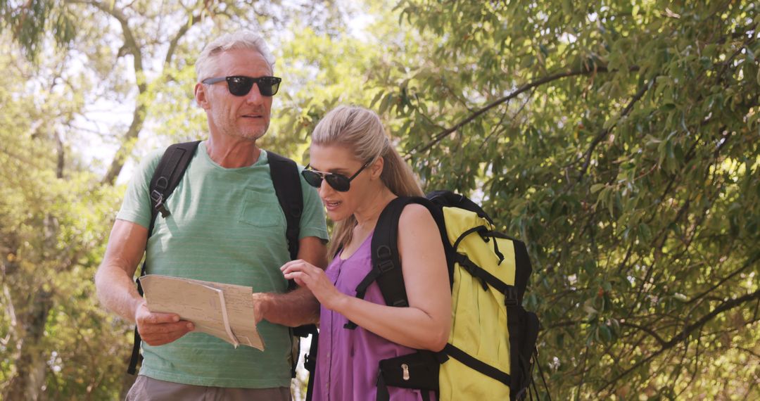 Senior Couple Hiking and Navigating with Map in Forest