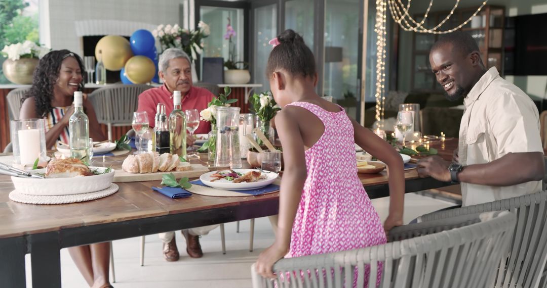 Multigenerational family enjoying al fresco dinner with string lights, bread and celebration