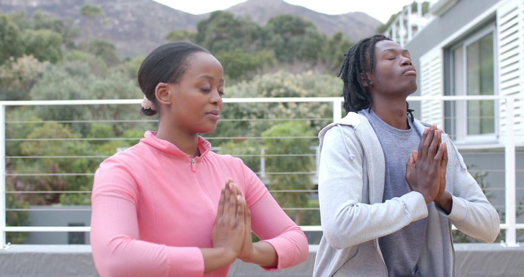 Couple Practicing Meditation on Sunlit Terrace with Mountain View for Wellness