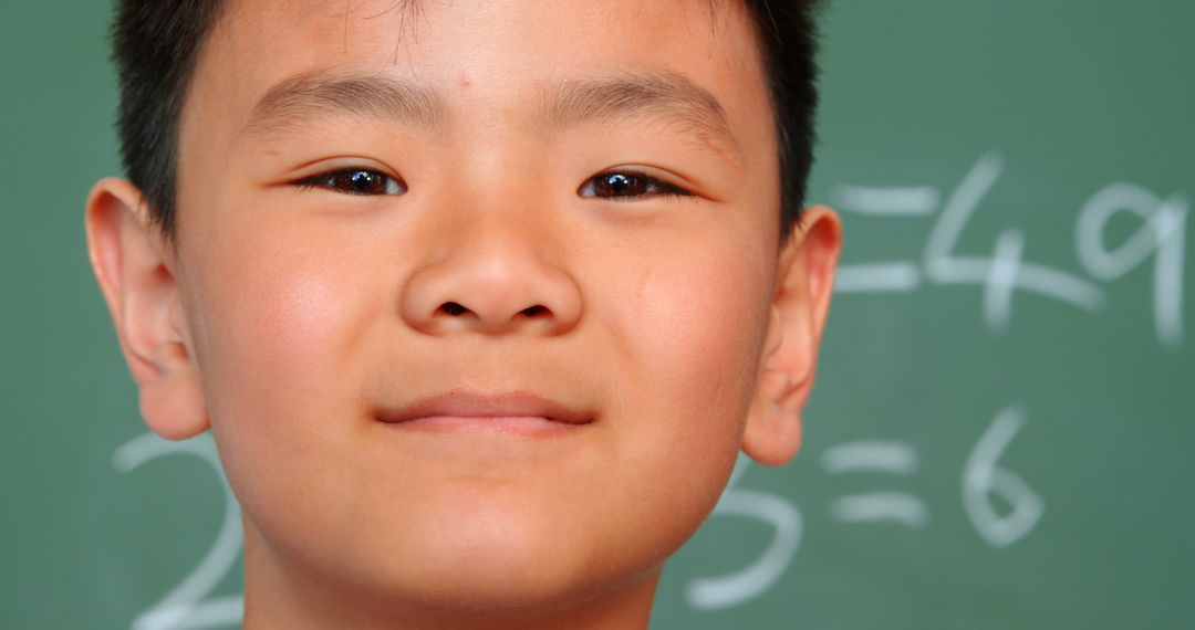 Smiling Schoolboy in Classroom with Chalkboard Background