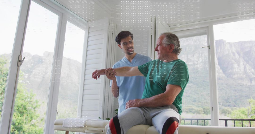Therapist guiding senior man through shoulder mobility exercise on rehab table with view