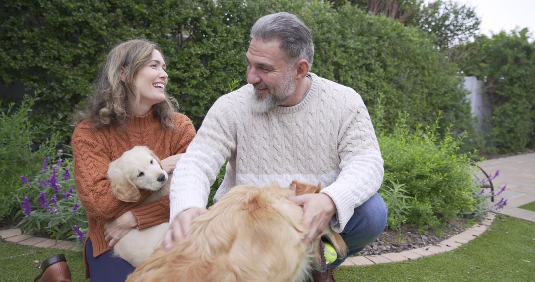 Couple Enjoying Outdoor Playtime with Golden Retrievers in Lush Garden
