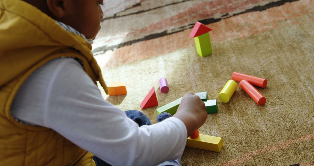 Young Boy Playing with Colorful Building Blocks on Carpet