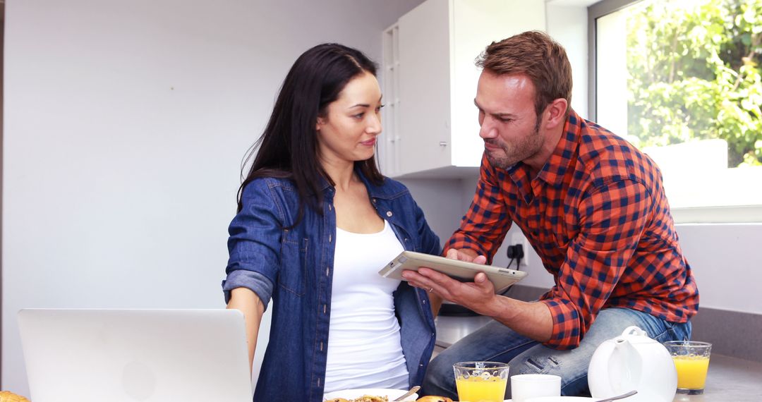 Couple Enjoying Breakfast While Watching Tablet in Modern Kitchen