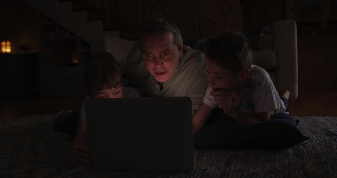 Father and Sons Watching a Laptop Screen Together in Dim Light - Free Images, Stock Photos and Pictures on Pikwizard.com