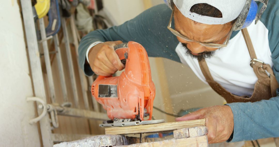 Focused Carpenter Using Jigsaw to Cut Wood Indoors - Free Images, Stock Photos and Pictures on Pikwizard.com