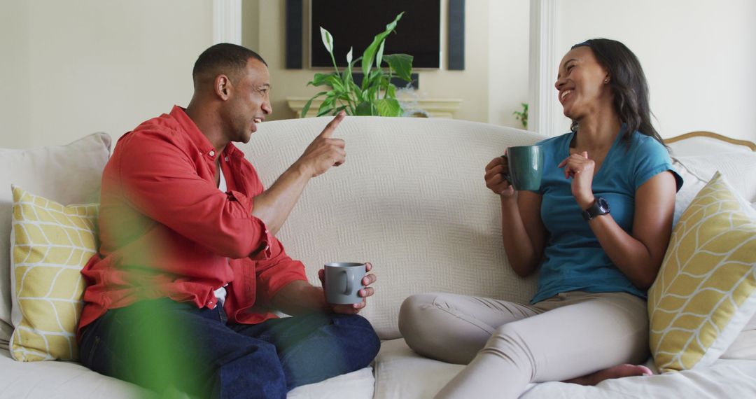 Happy Couple Relaxing on Sofa with Coffee Mugs at Home