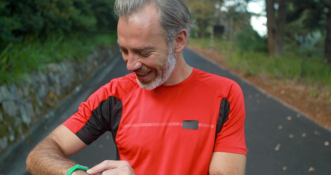 Mature Man Smiling While Checking Smartwatch During Outdoor Run - Free Images, Stock Photos and Pictures on Pikwizard.com