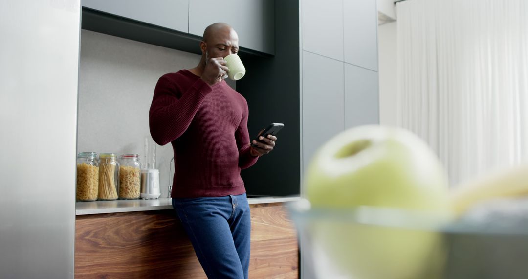 Man in Modern Kitchen Drinking Coffee and Using Smartphone - Free Images, Stock Photos and Pictures on Pikwizard.com