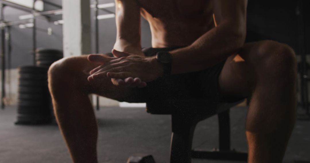 Man Rubbing Chalk in Hands on Bench in Gym Weightlifting Area