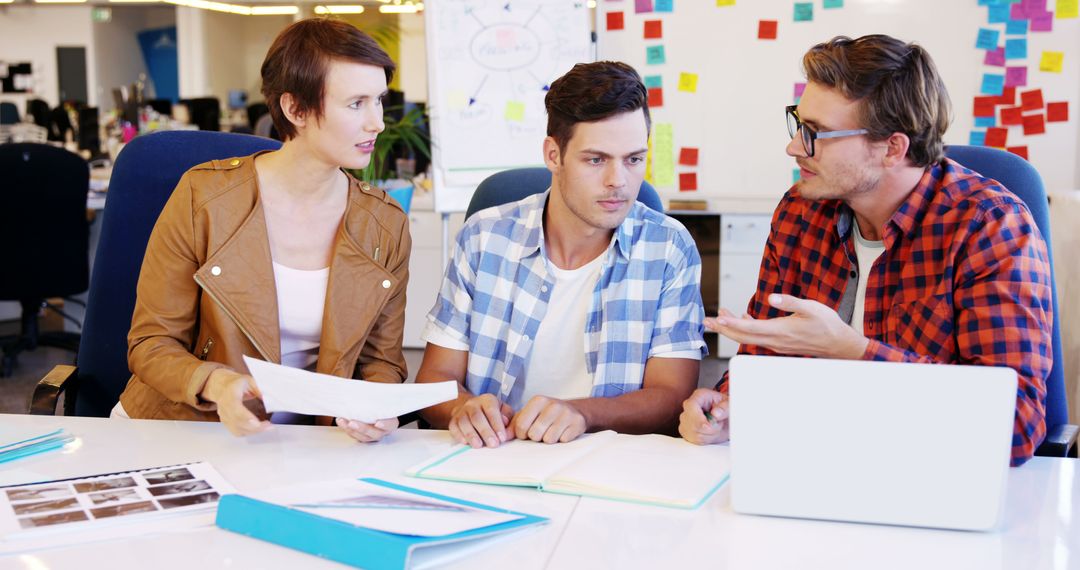 Creative Team Collaborates in Modern Office with Laptops and Documents