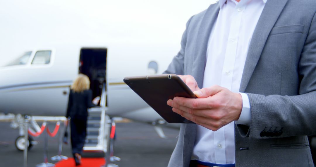 Businessman Using Tablet with Private Jet in Background During Travel - Free Images, Stock Photos and Pictures on Pikwizard.com