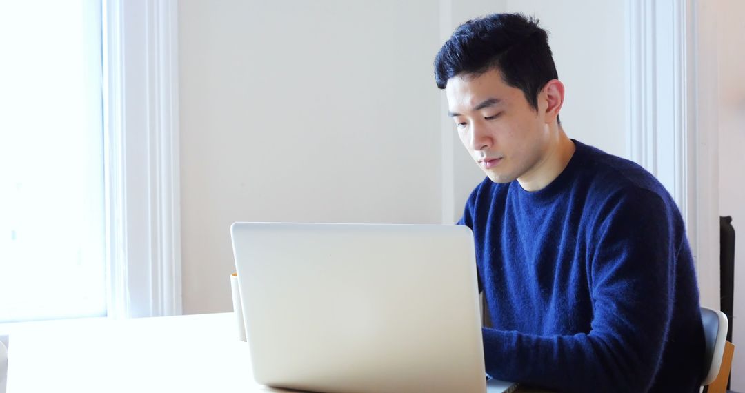 Focused Man Working on Laptop in Minimalistic Setting