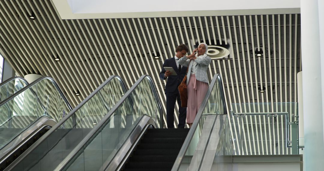 Business Professionals Talking on Escalator in Modern Office - Free Images, Stock Photos and Pictures on Pikwizard.com