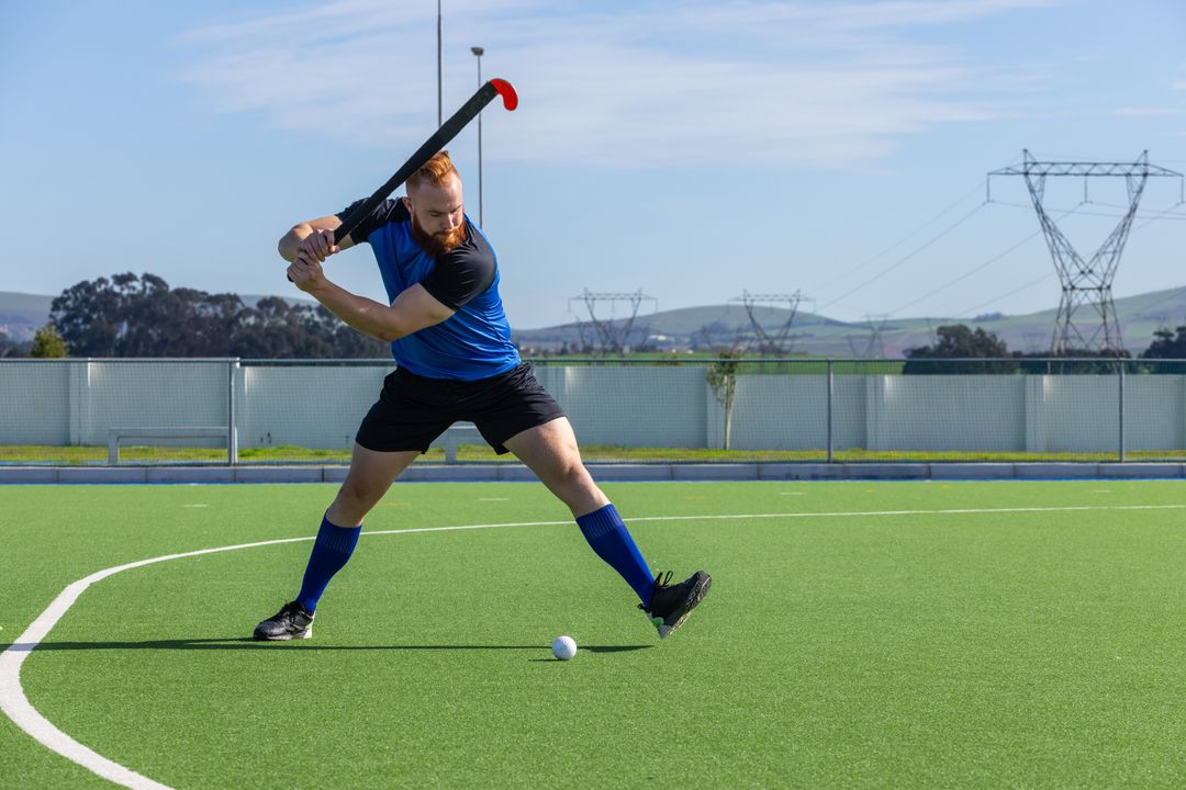Dynamic Athlete Preparing to Strike on Field Hockey Pitch