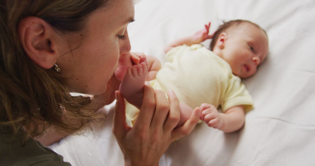 Image of happy caucasian mother kissing feet of newborn baby - Free Images, Stock Photos and Pictures on Pikwizard.com