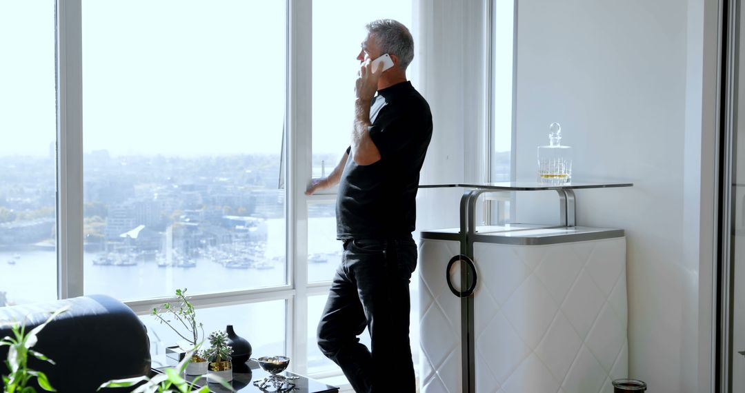 Businessman Talking on Phone By Window in Modern Office - Free Images, Stock Photos and Pictures on Pikwizard.com