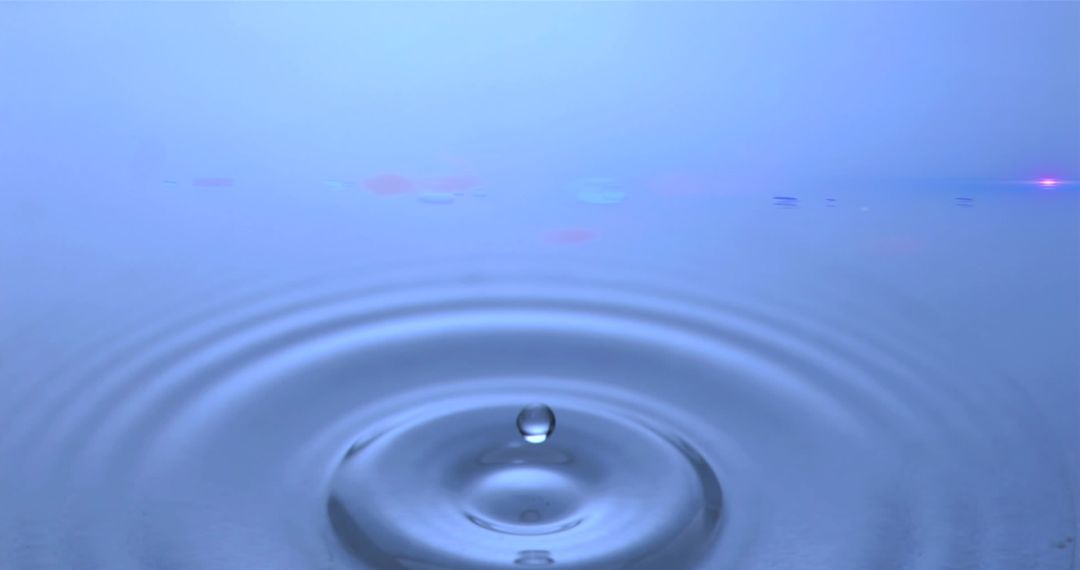 Water Droplet Creating Ripples on Blue Surface